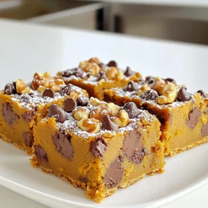 - 1 cup canned pumpkin puree - 1/2 cup unsalted butter, softened - 1 cup brown sugar, packed - 1/2 cup granulated sugar - 2 large eggs - 2 teaspoons vanilla extract - 2 cups all-purpose flour - 1 teaspoon baking soda - 1/2 teaspoon baking powder - 1 teaspoon ground cinnamon - 1/2 teaspoon ground nutmeg - 1/4 teaspoon salt - 1 cup semi-sweet chocolate chips - 1/2 cup chopped walnuts (optional) When you gather your ingredients, freshness is key. I love using canned pumpkin puree for its easy access and rich flavor. Make sure your butter is softened to mix well with the sugars. Brown sugar adds moisture and depth, while granulated sugar gives a nice balance. Eggs bind the mixture together, and vanilla adds a lovely aroma. All-purpose flour is perfect here. It gives the bars a nice texture. Baking soda and baking powder work together to help them rise. Cinnamon and nutmeg bring warmth and spice that scream fall. Salt enhances all the flavors, so don’t skip it. Chocolate chips are a must for sweetness. If you want a crunchy texture, add chopped walnuts. They give a nice contrast to the soft bars. Now that you have everything ready, let’s dive into the fun part—baking these delicious treats! First, preheat your oven to 350°F (175°C). This step gets the oven ready for baking. Next, take a 9x13-inch baking pan. Grease it with butter or cooking spray. For easy removal, line it with parchment paper. Make sure to leave some paper hanging over the edges. In a large bowl, cream together the softened butter, brown sugar, and granulated sugar. Mix until it looks light and fluffy. Then, add the canned pumpkin, eggs, and vanilla extract. Stir everything until the mixture is smooth and well blended. In a separate bowl, whisk together the all-purpose flour, baking soda, baking powder, ground cinnamon, ground nutmeg, and salt. This mix is key for flavor and texture. Gradually add the dry mix to the wet mix, stirring gently until just combined. Be careful not to stir too much; we want soft bars, not tough ones. Now, pour the batter into the greased baking pan. Use a spatula to spread it evenly. Bake your cookie bars for about 25 to 30 minutes. To check if they are done, insert a toothpick into the center. If it comes out clean, they are ready. After baking, let them cool in the pan for about 10 minutes. Use the parchment paper to lift them out and cool completely on a wire rack. To make the best cookie bars, avoid overmixing the batter. Overmixing can make your bars tough. Mix until the flour just disappears. This keeps them soft and chewy. Check for doneness by inserting a toothpick into the center. If it comes out clean or with a few crumbs, they are ready. Make sure not to bake too long. Keep an eye on them to prevent dryness. For added flavor, consider using spices like ginger or cloves. These spices boost the warm taste of pumpkin. They give your cookie bars a cozy touch. Using room temperature ingredients is also key. It helps the butter blend well with sugars. This step makes your bars light and fluffy. Presentation matters! Dust your bars with powdered sugar for a sweet look. A drizzle of white chocolate can add flair too. Pair your cookie bars with a cup of coffee or milk. This combo makes for a delightful treat. Serve them warm for an extra comforting experience. {{image_2}} You can change the flavor of your cookie bars easily. Try using other purees instead of pumpkin. Sweet potato puree adds a nice twist. Butternut squash works well too. Each puree brings its own taste. Changing spices can also create new flavors. If you want a warm kick, add ginger. Cardamom or allspice can give a unique touch. If you want dairy-free bars, swap butter for coconut oil. You can also use a vegan butter. This keeps the bars just as tasty. For chocolate chips, try white chocolate or dark chocolate. You can even use carob chips for a different flavor. Adding nuts or dried fruits makes your bars special. Walnuts add crunch, but pecans are great too. Dried cranberries or cherries add a sweet burst. To create a marbled effect, swirl in some cream cheese or peanut butter. This looks pretty and tastes amazing! To keep your pumpkin chocolate chip cookie bars fresh, store them properly. Place the bars in an airtight container. This helps prevent them from drying out. Make sure to separate layers with parchment paper. This keeps them from sticking together. You can also wrap them tightly in plastic wrap. This works well if you do not have a container. A cool, dry place is best for storage. Avoid direct sunlight and heat. Your cookie bars will stay fresh for about five days this way. For longer storage, consider freezing them. Freezing is a great way to keep your cookie bars for later. Cut them into squares or rectangles first. This makes it easy to grab a piece when you want one. Place the pieces in a single layer on a baking sheet. Freeze them for about an hour. Once frozen, transfer them to a freezer-safe bag or container. Label it with the date. To thaw, simply take out the desired number of bars. Let them sit at room temperature for about 30 minutes. If you want them warm, pop them in the microwave for a few seconds. This will make the chocolate chips melt again, giving you that fresh-baked taste. You can swap some ingredients for better choices. Use less sugar or a sugar substitute. You can also replace half of the butter with applesauce. Use whole wheat flour instead of all-purpose flour for more fiber. Add oats for a chewy texture. These changes can make your bars tastier and healthier. Yes, you can use fresh pumpkin! Start by cooking the pumpkin until soft. You can roast it or steam it. Once soft, mash it and let it cool. Then, measure out one cup of the fresh puree. It adds a nice flavor and makes the bars fresh! If your bars turn out too cake-like, it might be due to overmixing. Be careful when you mix the dry and wet ingredients. You want to mix just until combined. If you like a denser bar, try reducing the baking powder slightly. This will make them chewier. These cookie bars can last up to a week when stored right. Keep them in an airtight container at room temperature. If you want them to last longer, you can freeze them. They stay good in the freezer for up to three months. Absolutely! A cream cheese frosting pairs well with these bars. You can whip up a simple frosting with cream cheese, butter, and powdered sugar. Spread it on top after the bars cool down. It adds a delicious twist and makes them even more special! You learned how to make delicious pumpkin chocolate chip cookie bars with simple steps. Using key ingredients like pumpkin puree, butter, and chocolate chips creates a tasty treat. Remember, mixing well and avoiding overbaking are key tricks. You can customize flavors and enhance texture with easy swaps. Finally, store leftovers properly and enjoy them later. Baking these bars is fun, and sharing them makes it even better!