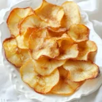 To make cinnamon sugar apple chips, gather these key items: - 3 medium-sized apples (such as Honeycrisp or Fuji) - 2 tablespoons granulated sugar - 1 teaspoon ground cinnamon - Pinch of salt - Lemon juice (for coating) These ingredients create a perfect balance of sweet and spiced flavors. The apples serve as the base, while the sugar and cinnamon add a nice touch. Choosing the right apples is crucial. I recommend these tasty options: - Honeycrisp: Sweet, crisp, and juicy. - Fuji: Sweet with a firm texture. - Granny Smith: Tart and crisp, perfect for balance. These varieties hold up well during baking and give great flavor. Feel free to get creative! Here are some optional ideas: - Nutmeg: Adds warmth and depth. - Vanilla extract: Enhances sweetness. - Brown sugar: Gives a rich flavor. You can play with these extras to make the chips your own. Enjoy experimenting! {{ingredient_image_1}} Start by washing your apples well. I like to use Honeycrisp or Fuji apples. They are sweet and crisp. After washing, dry them with a clean towel. Next, slice the apples thinly. Use a mandoline or a sharp knife. Aim for about 1/8 inch thick. Thin slices will crisp better. In a small bowl, mix the sugar, cinnamon, and a pinch of salt. This blend adds great flavor. Take your apple slices and place them in a large bowl. Drizzle a little lemon juice on top. This helps prevent browning. Toss the apple slices gently to coat. Now, sprinkle the cinnamon-sugar mix over them. Make sure every slice gets an even coat. Preheat your oven to 200°F (93°C). Line two baking sheets with parchment paper. Lay the apple slices in a single layer. Make sure they don’t overlap. Bake them for about 2 hours. Flip the slices halfway for even crispiness. Keep an eye on them. They are done when crispy and lightly browned. Let them cool completely. They will crisp up as they cool. Enjoy your crunchy snack! To get your apple chips super crispy, use a mandoline for even slices. Slice the apples to about 1/8 inch thick. Thin slices help the chips bake evenly. Lay the slices in one single layer on the baking sheet. If they overlap, they won’t cook well. Bake them slowly at a low temperature, around 200°F (93°C). Flip the slices halfway through to ensure even cooking. Keep an eye on them. They should be lightly browned and crisp when done. If you have leftover apple chips, store them in an airtight container. This keeps them fresh and crunchy. You can also use a resealable bag, but remove as much air as possible. Keep them in a cool, dry place, away from sunlight. They can last for about a week if stored right. If you want them crisp again, reheat them in the oven for a few minutes. One common mistake is not drying the apple slices enough before baking. Make sure to dry them well after washing. Another mistake is using thick slices. Thick slices take longer to cook and may turn out soft. Don't skip the lemon juice; it prevents browning and adds flavor. Lastly, avoid overcrowding the baking sheets. Giving each slice space helps them crisp up nicely. Pro Tips Choose the Right Apples: Opt for sweeter varieties like Honeycrisp or Fuji for a tastier chip. Their natural sweetness enhances the flavor of the cinnamon sugar. Uniform Slices: Use a mandoline for perfectly uniform slices. This ensures even cooking and crispiness across all chips. Watch the Baking Time: Keep an eye on the apple chips as they bake. Depending on your oven, the time may vary slightly, so check for crispiness and light browning. Storage Tips: Once cooled, store the apple chips in an airtight container to maintain their crispness. They make a great snack for days! {{image_2}} You can add more flavors to your cinnamon sugar apple chips. Try adding nutmeg for a warm spice. Just a pinch will do! If you like sweet flavors, vanilla extract works well too. A few drops will make your chips taste special. These small changes can take your snack to the next level. You don’t have to use plain sugar for sweetness. Brown sugar adds a rich flavor. It gives your chips a lovely caramel note. Honey is another option. Drizzle it over the apple slices for a natural sweetness. Both options work great and change the flavor a bit. Why stop at apples? You can use other fruits to make chips. Pears are a tasty choice that pairs well with cinnamon. Bananas also work; just slice them thin. Try experimenting with peaches or mangoes if you’re feeling adventurous. Each fruit will give you a unique and delicious chip! To keep your cinnamon sugar apple chips fresh, store them in an airtight container. You can use a glass jar or a plastic bag. Avoid using containers that let air in. Make sure the chips are completely cool before sealing them. This keeps moisture away and helps them stay crispy. To maintain the crispiness, keep the apple chips away from heat and light. Store them in a cool, dark place. If you notice any moisture in the container, transfer the chips to a new one. You can also add a small packet of silica gel to absorb moisture. This helps keep your snack crunchy for longer. Homemade apple chips can last for up to two weeks when stored correctly. If you notice any changes in texture or taste, it’s best to toss them. However, for the best flavor and crunch, enjoy them within the first week. Trust me, they make a great snack, and you won’t want to let them sit around for too long! Yes, you can use a dehydrator to make apple chips. A dehydrator dries the apples slowly, which helps keep their flavor and nutrients. Slice the apples thin, like you would for the oven. Set the dehydrator to 135°F (57°C). Dry the apple slices for about 6 to 8 hours. Check them often until they reach a crisp texture. Using a dehydrator can give you a different, but tasty, result. To prevent browning, use lemon juice. After slicing the apples, drizzle a little lemon juice over them. Toss the slices gently to coat them. The lemon juice stops oxidation, which causes browning. It also adds a nice flavor. Another tip is to soak the slices in a mix of water and lemon juice for a few minutes before coating them in cinnamon sugar. Cinnamon sugar apple chips offer several benefits. Apples are high in fiber, which helps digestion. They also provide vitamins like A and C. Cinnamon has antioxidants and may help with blood sugar levels. While sugar adds some calories, you can control how much you use. When baked, these chips are a better snack option than chips or candy. Enjoy them guilt-free! We've covered key ingredients, steps, and tips for making delicious apple chips. You can choose the best apples and even customize flavors. Remember to use simple tricks for crispiness and proper storage to keep them fresh. Explore options like different fruits and sweeteners to mix things up. Making apple chips is fun and rewarding. Enjoy these tasty snacks while knowing they are good for you!